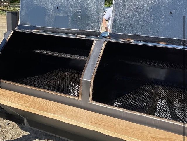 Both smoker chambers open, showing the cooking grates and the center smoke box that feeds them